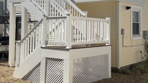 A two-story building with a white exterior, a balcony on the upper floor, and a staircase leading to the second floor. - 2nd floor of duplex. Bay view, sunsets, beach, activities. Great family getaway! (Ship Bottom)