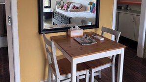 Een kamer met een eettafel, stoelen, een grote spiegel, een bank en een keukenhoek.