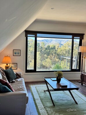 Une pièce avec une grande fenêtre, un canapé, une table et une lampe.