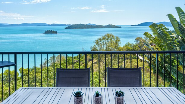 Uma varanda com vista para um mar tranquilo e ilhas distantes.