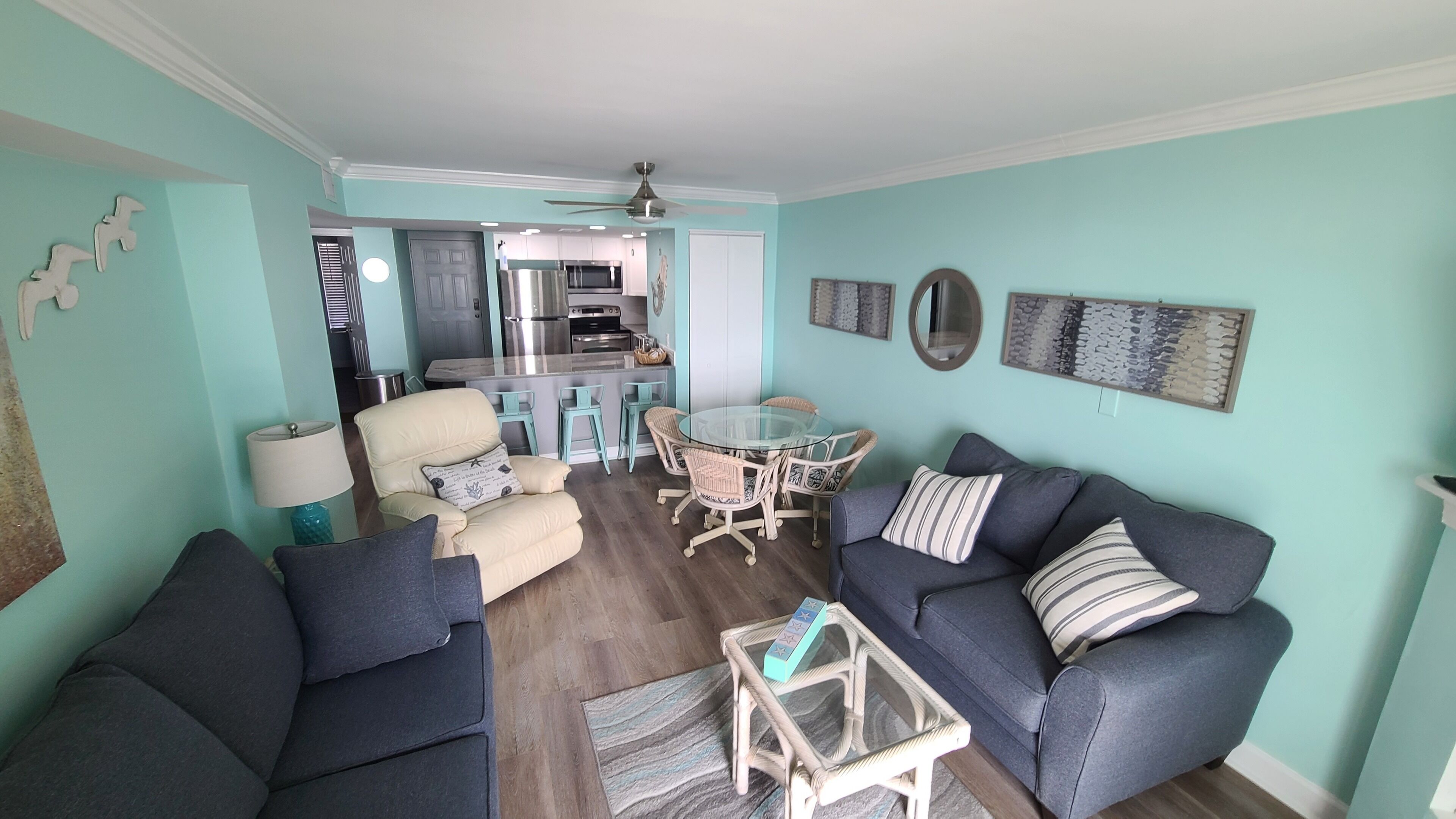 A living room with a sofa, armchair, coffee table, and a dining area with a table and chairs.