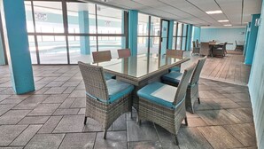 Una sala conferenze con tavolo in vetro e sedie in vimini, ampie finestre e vista su una piscina.