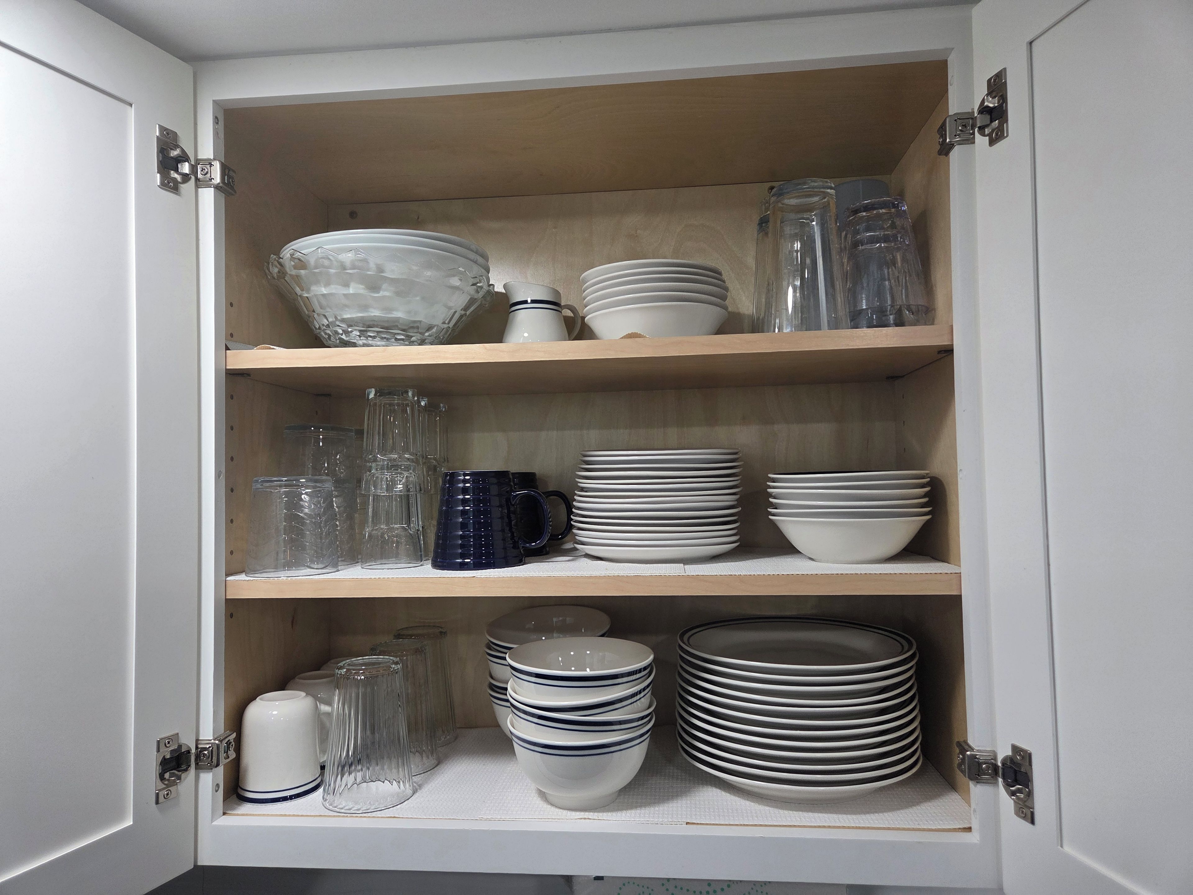 A cabinet with multiple shelves containing various glassware and dishes.