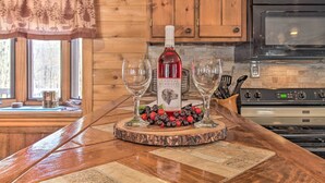 Una encimera de madera con una botella de vino Chateau Morisette, dos copas y una guirnalda decorativa de bayas.