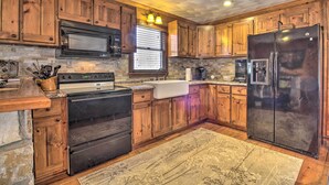 Una cocina con armarios de madera, un refrigerador de acero inoxidable, un microondas y una estufa.