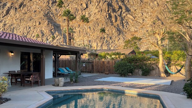 Un jardin avec une piscine, une terrasse dotée de mobilier d’extérieur et une vue sur les montagnes.