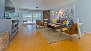 Un salon moderne avec un canapé, des fauteuils, une table basse et un téléviseur.