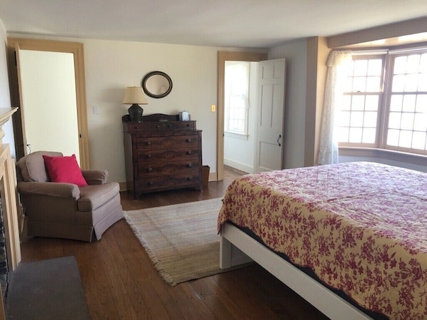Un dormitorio con cama, cómoda, silla y puerta.