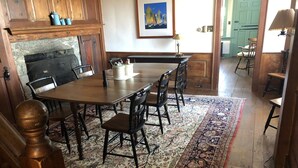 Un comedor con mesa y sillas de madera, alfombra estampada y chimenea.