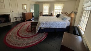 Un dormitorio con cama, cómoda y chimenea.