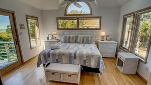 A bedroom with a bed, bedside tables, a bench, and large windows. - Sound's Great! | Sound Front | Private Pool | Corolla (Corolla)
