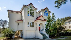 A two-story house with a white exterior, red roof, and a garage. - Sound's Great! | Sound Front | Private Pool | Corolla (Corolla)