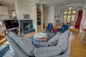 Un salon spacieux comprenant un grand canapé, un téléviseur, une cheminée et un coin repas avec des chaises et une table.