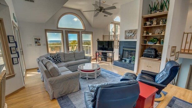 A spacious living room with a large sofa, a coffee table, and a fireplace. - Sound's Great! | Sound Front | Private Pool | Corolla (Corolla)