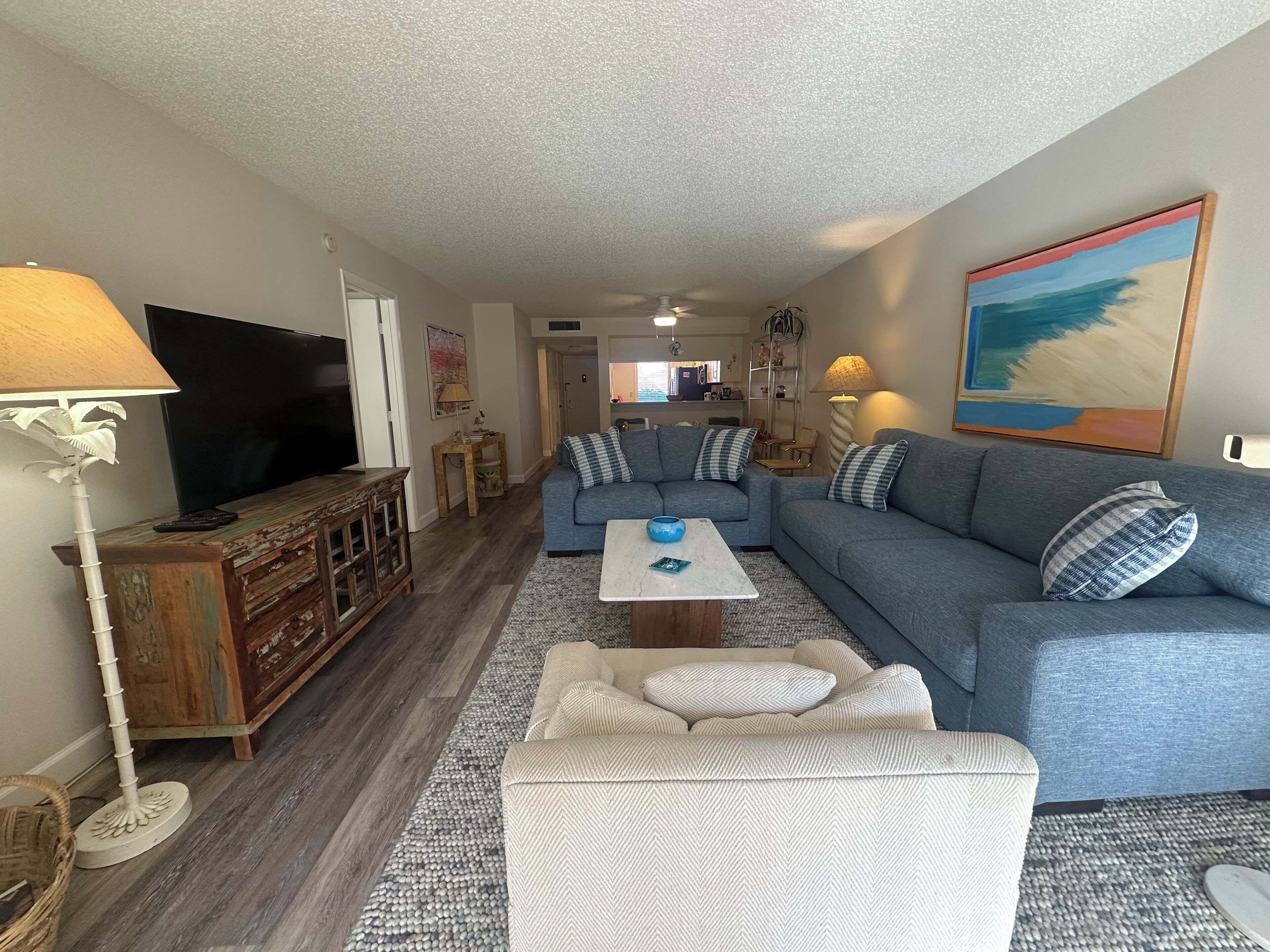 A living room with a sectional sofa, a TV, a coffee table, and a lamp.