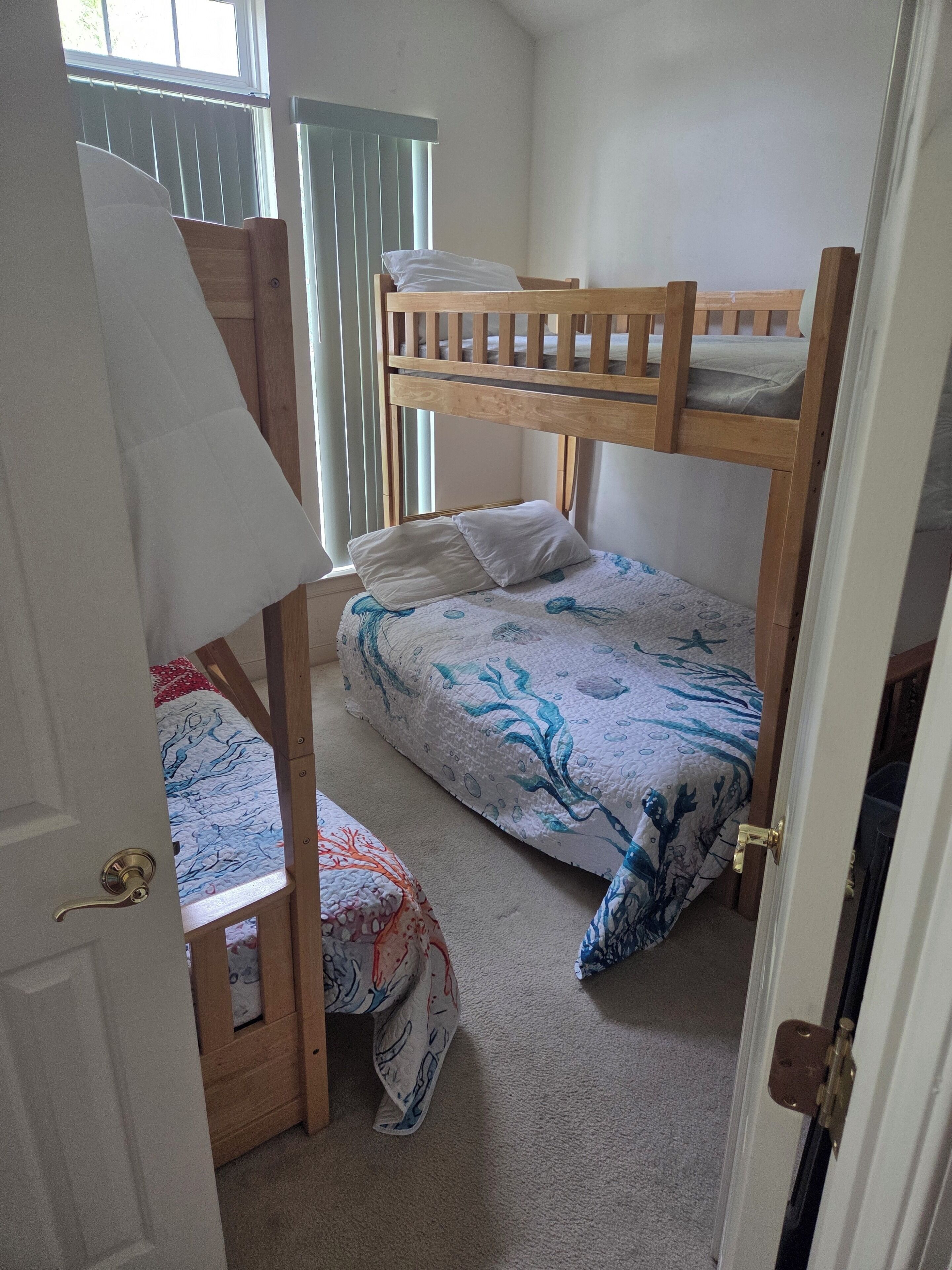 A room with bunk beds, a door, and a window with blinds.