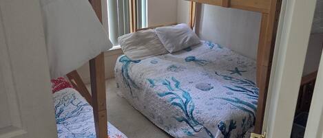 A room with bunk beds, a door, and a window with blinds.