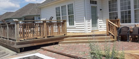 A house with a wooden deck, a stone fire pit, and a brick patio.