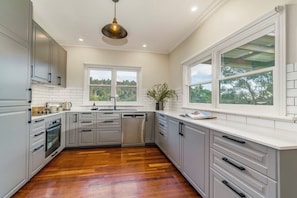 Una cocina moderna con armarios blancos, piso de madera y un amplio ventanal con vistas al exterior.