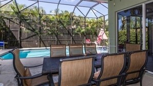 Et udendørs poolområde med et overdækket siddeområde og udsigt over poolen.