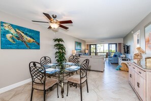 A dining area with a glass table, metal chairs, and a ceiling fan.