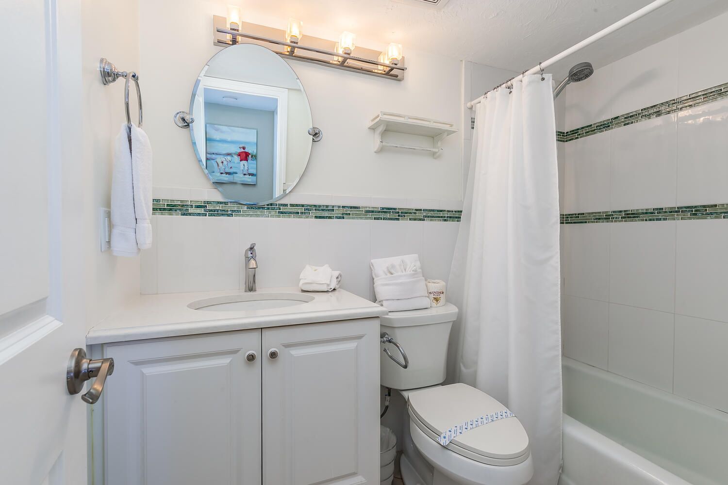 A bathroom with a white sink, a mirror, a toilet, and a shower.