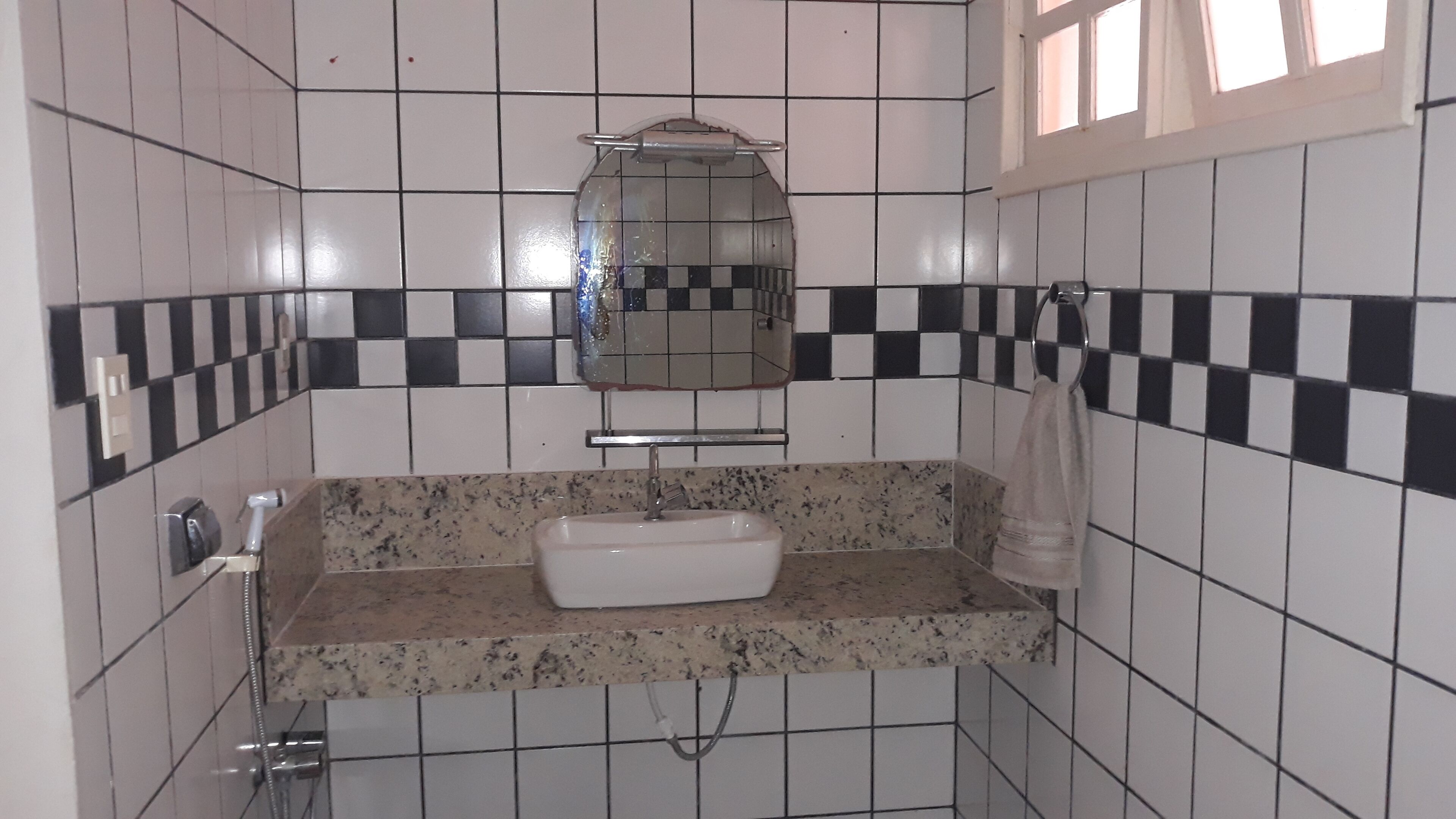 Ein Badezimmer mit einem weißen Waschbecken, einem Spiegel und einem Handtuchhalter.