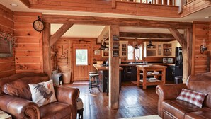 L’intérieur d’un chalet rustique, avec des murs en bois, un coin repas et des canapés en cuir.