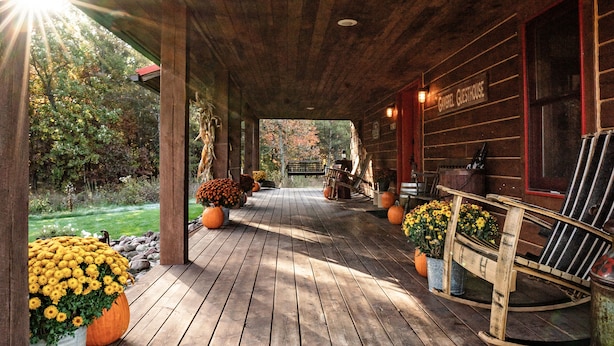 Une véranda en bois avec un banc, un fauteuil à bascule et une enseigne sur laquelle on peut lire : « Camrel Guesthouse ».