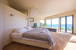 Un dormitorio con una cama grande, una mesita de noche, una ventana con vistas y un ventilador de techo.