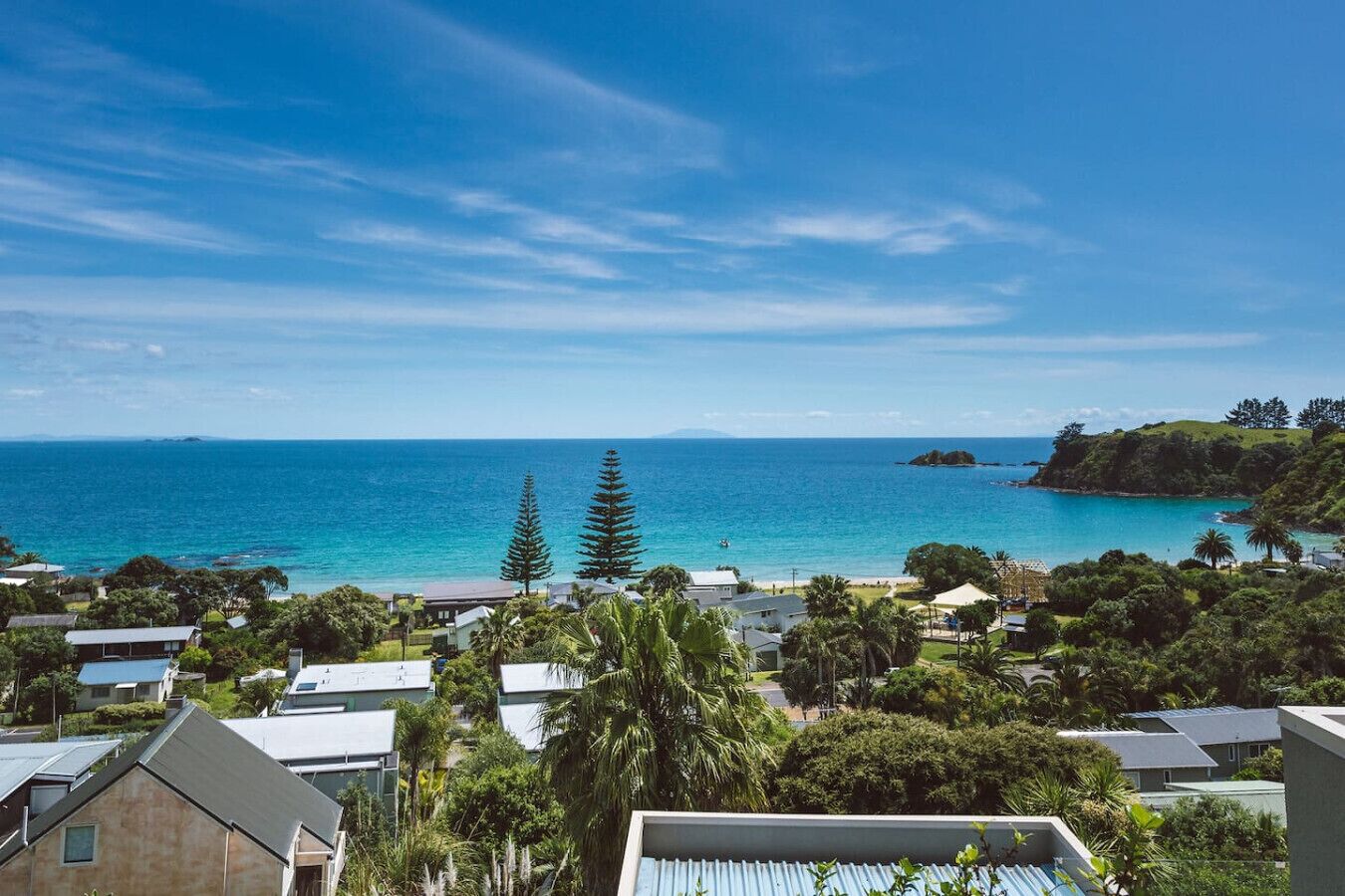 Un quartier résidentiel situé sur la côte, avec des maisons, un ciel bleu dégagé et une vue sur la mer.