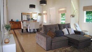 A modern living room with a grey sectional sofa, a dining area, and a kitchen in the background. - Dream, Dam, heated pool, 4 suites. Coffee shop, Restaurant, Burger joint.<br><br> <br><br><br><br><br><br><br><br><br> (Paranapanema)