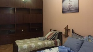 Une chambre à coucher comprenant un lit, une table de chevet, une armoire en bois et un tableau accroché au mur.