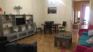 Un salon équipé d’un téléviseur, d’un canapé, d’une table basse et d’un coin repas avec des chaises.