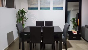 Un coin repas avec une table et des chaises, une plante en pot et des œuvres d’art accrochées au mur.