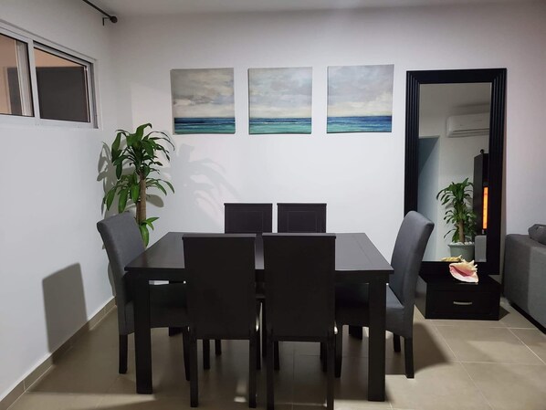 A dining area with a table and chairs, a potted plant, and artwork on the wall.