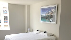 Camera d'albergo minimalista con un letto grande, un comodino, una lampada a parete e un quadro incorniciato.