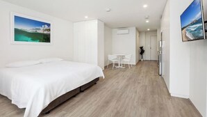 Una camera d'albergo con un letto, un tavolino, sedie e un frigorifero.