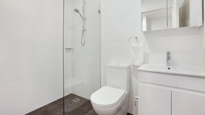 Un bagno moderno con doccia vetro, un water bianco e un lavandino con specchio sopra.