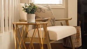 Ein gemütliches Wohnzimmer mit einer Couch, einem kleinen Tisch mit einer Pflanze, einem gemusterten Teppich und einer Treppe.