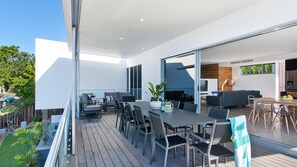 Ein moderner Essbereich im Freien mit einer Holzterrasse, Metallstühlen und einem Tisch.