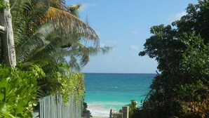 Un camino de concreto que lleva a una playa, con vista despejada al océano.