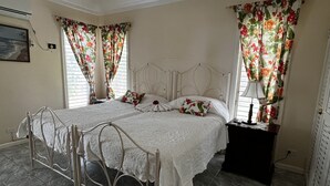 Un dormitorio con cama, cortinas, mesita de noche y lámpara.