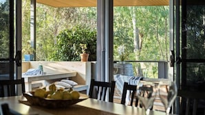 Un amplio espacio al aire libre con una mesa de madera, sillas y un frutero.