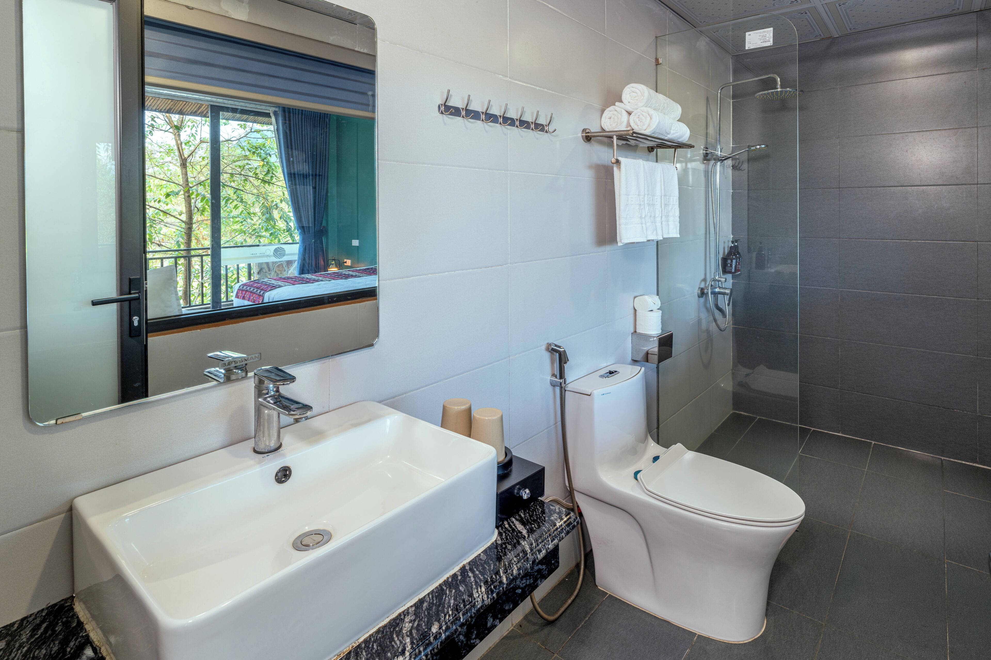 Un baño moderno con un espejo grande, un lavabo, un inodoro y una ducha.