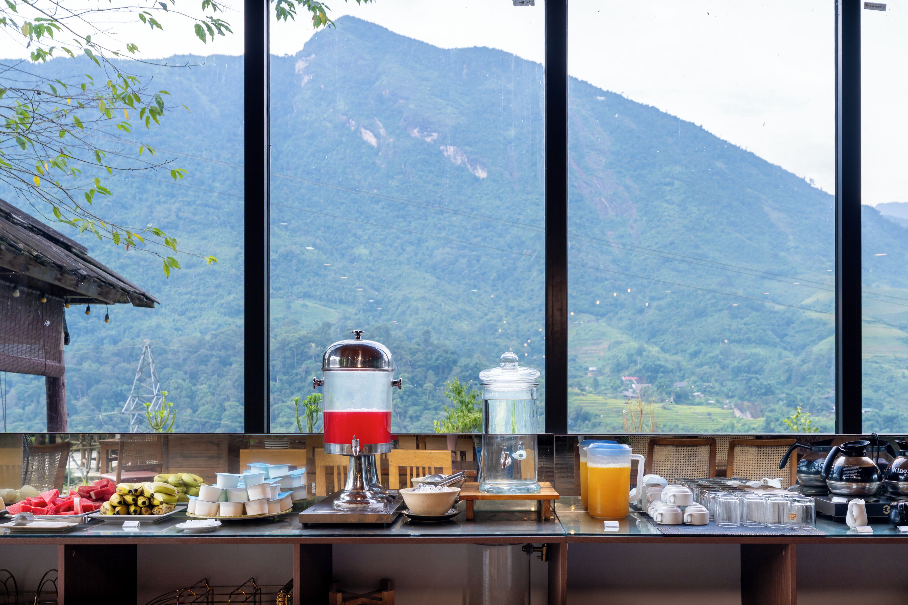 Un buffet proposant une variété de plats et une fontaine à boissons, avec une vue imprenable sur un paysage montagneux.
