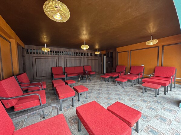 A waiting area with red chairs and ottomans, wooden paneling, and hanging lamps. -  Belle Maison Sapa Resort & Spa - Formerly Sapa Eco Villas & Spa (Ta Van)