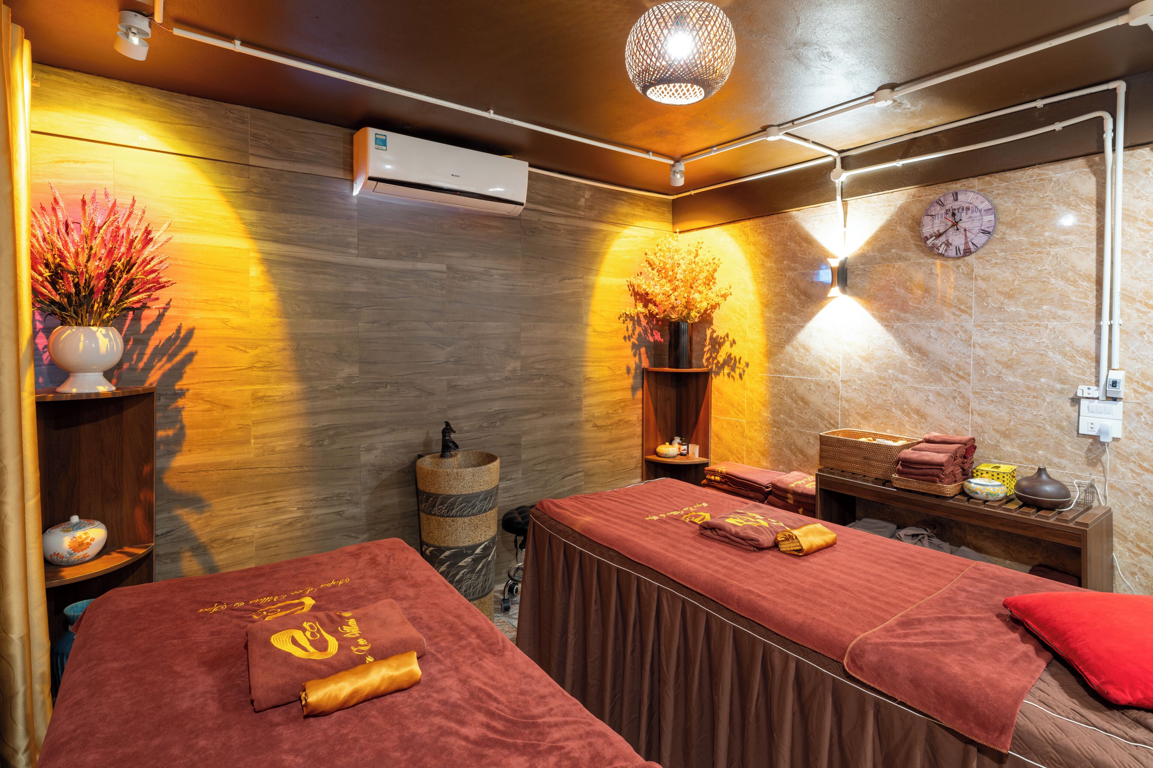 Un cuarto de spa con dos camillas de masaje, un reloj y un jarrón decorativo.