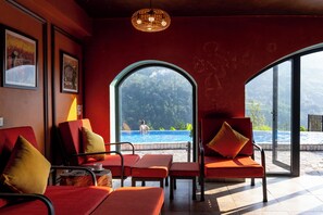 A room with red walls, a large window overlooking a pool, and several red chairs with cushions. -  Belle Maison Sapa Resort & Spa - Formerly Sapa Eco Villas & Spa (Ta Van)