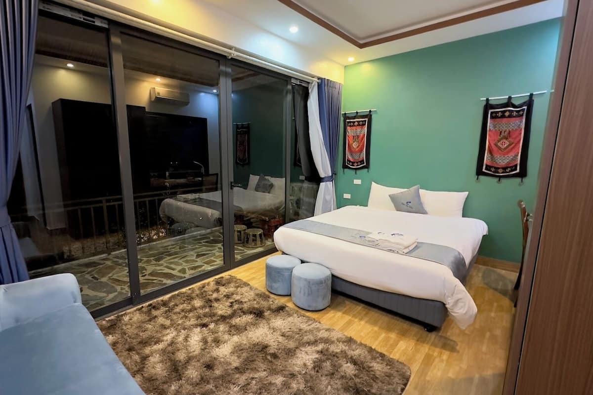 A modern bedroom with a large bed, a fluffy rug, and a sliding glass door leading to a balcony.
